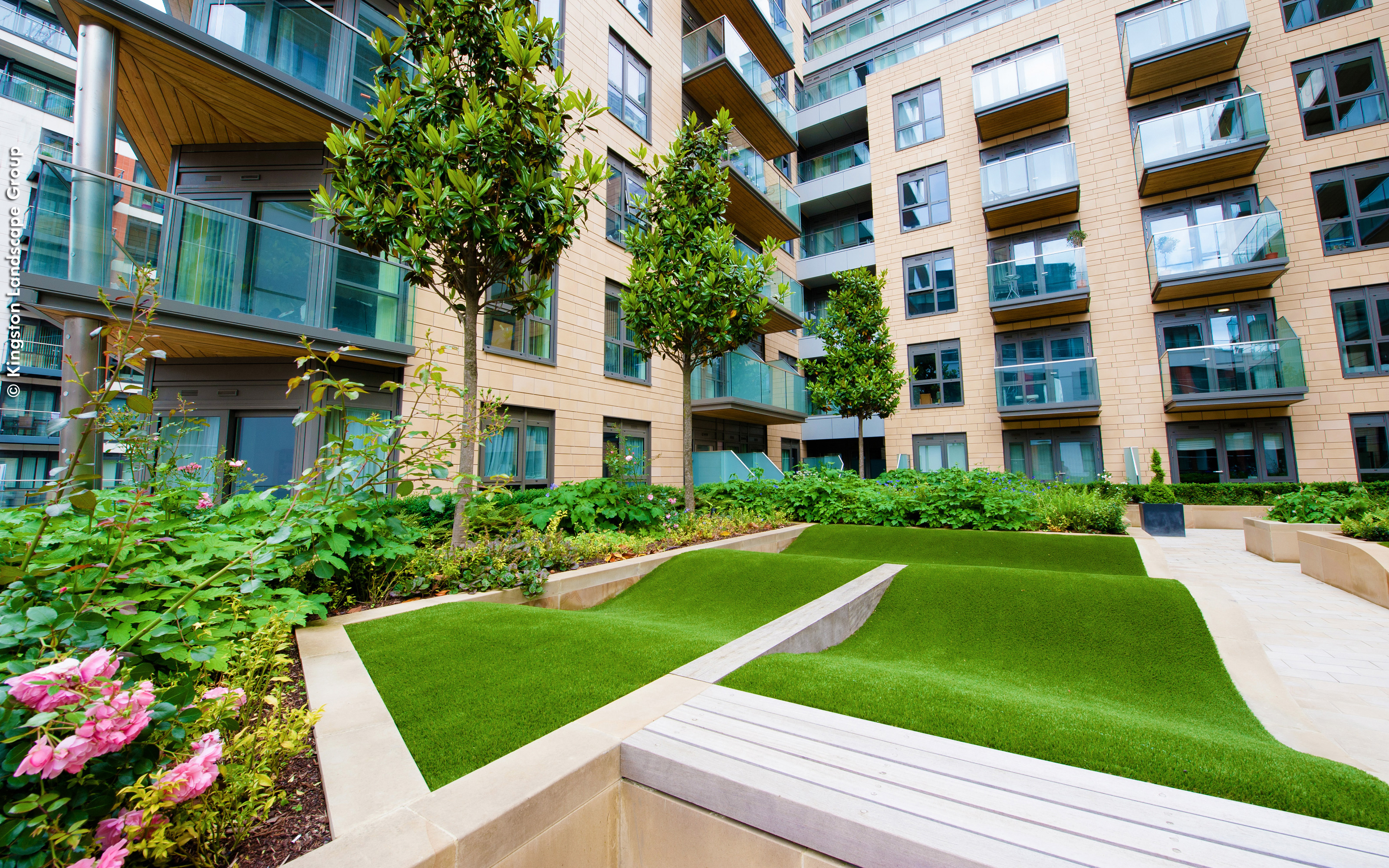 The courtyard is designed with rolling mounds of artificial grass. Courtyard with rolling mounds made from grass surrounded by residential blocks